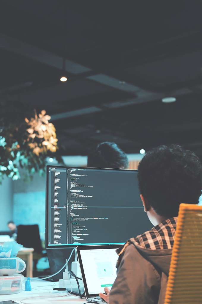 Programmer in front of a notebook and monitor.